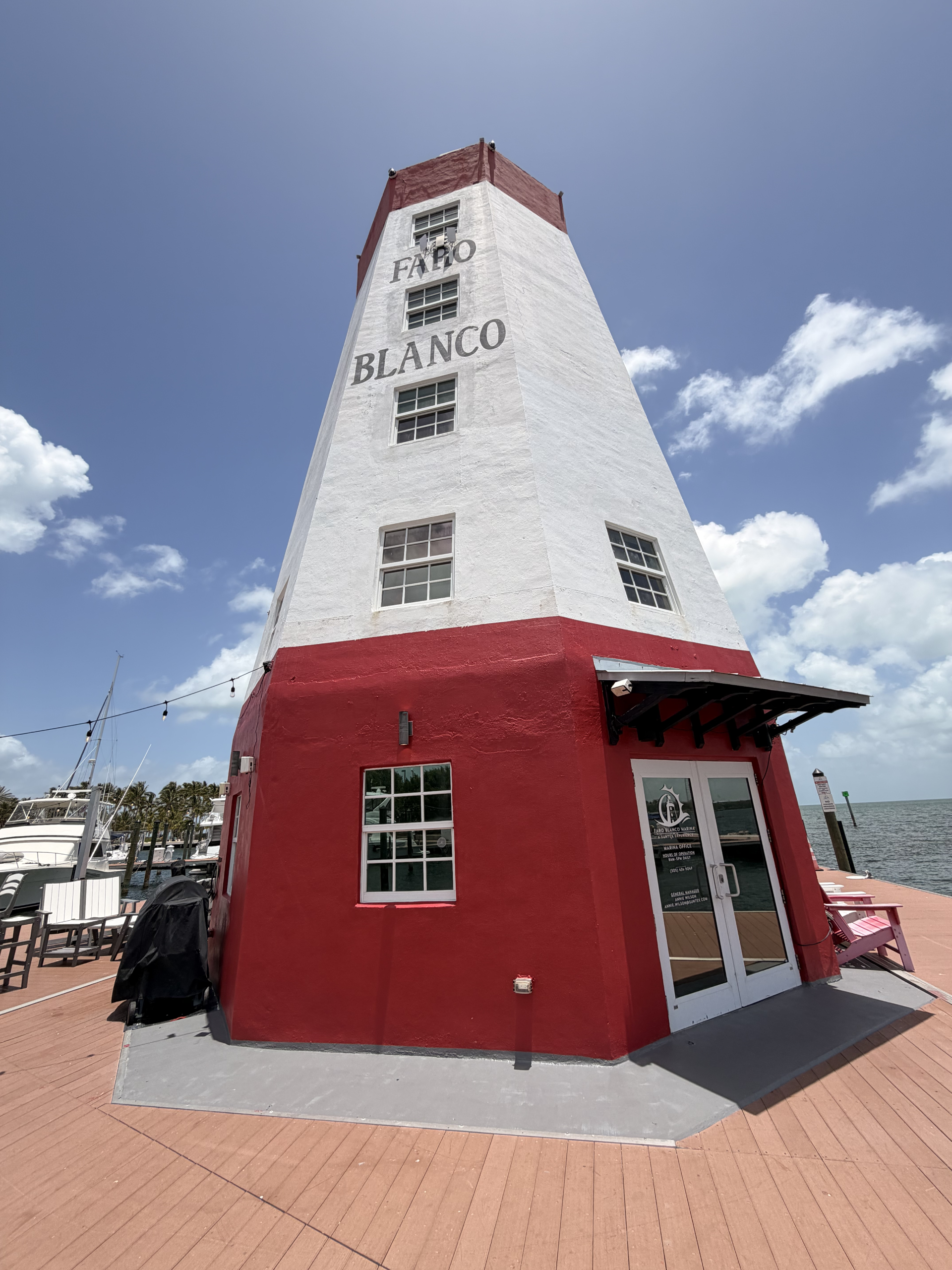 Red and white lighthouse with 'Faro Blanco' text under a blue sky.