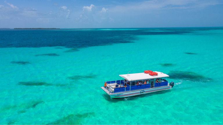 Small blue tour boat on clear turquoise ocean under a blue sky.