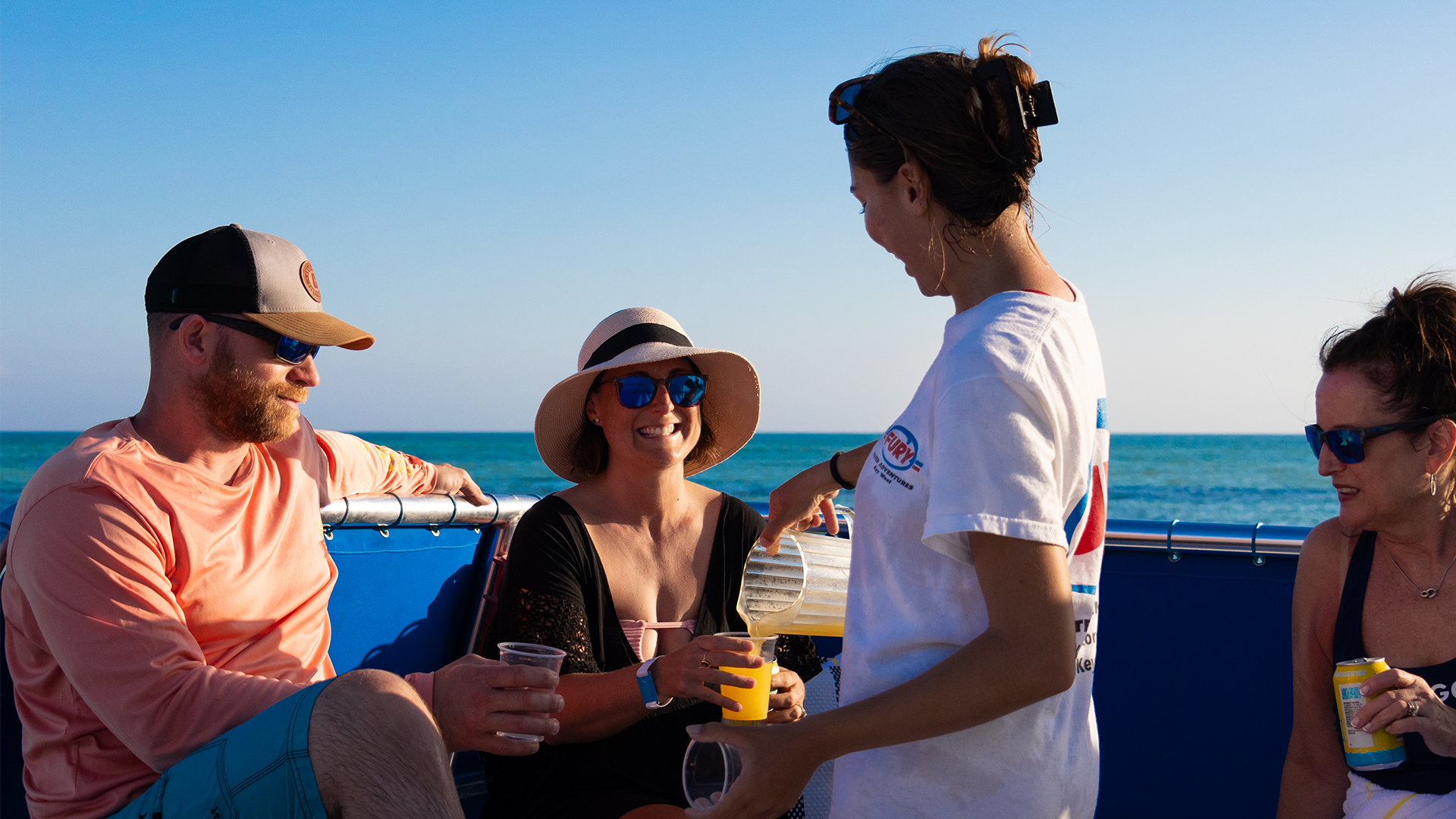 People enjoying drinks on a boat under a clear sky.