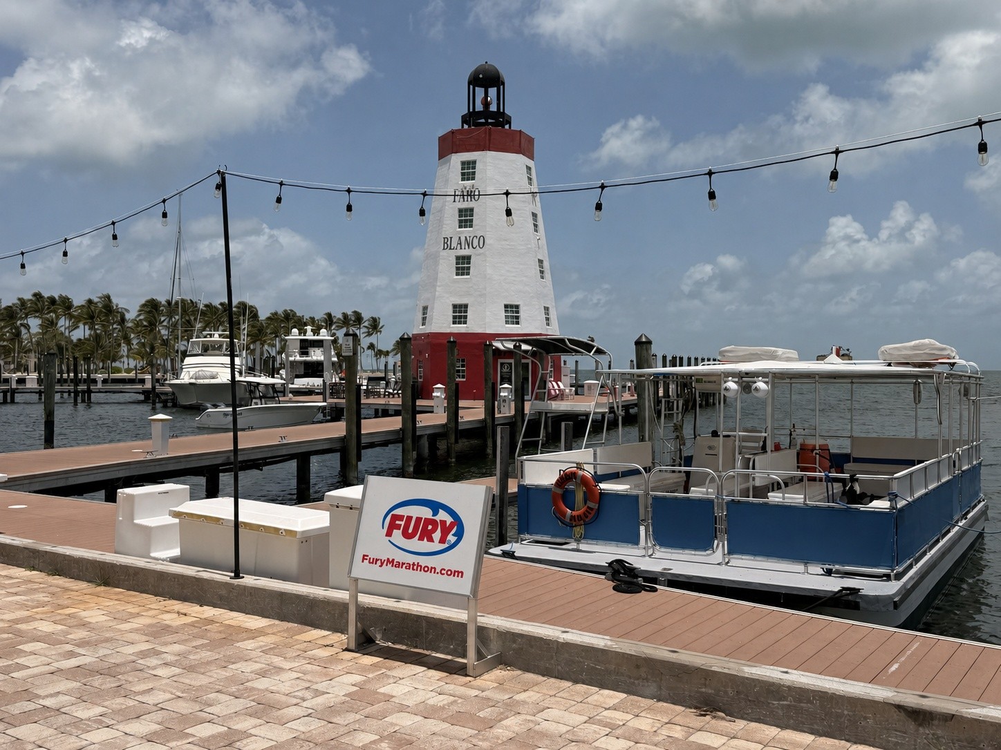 Docked boat beside a lighthouse with string lights and a Fury sign.